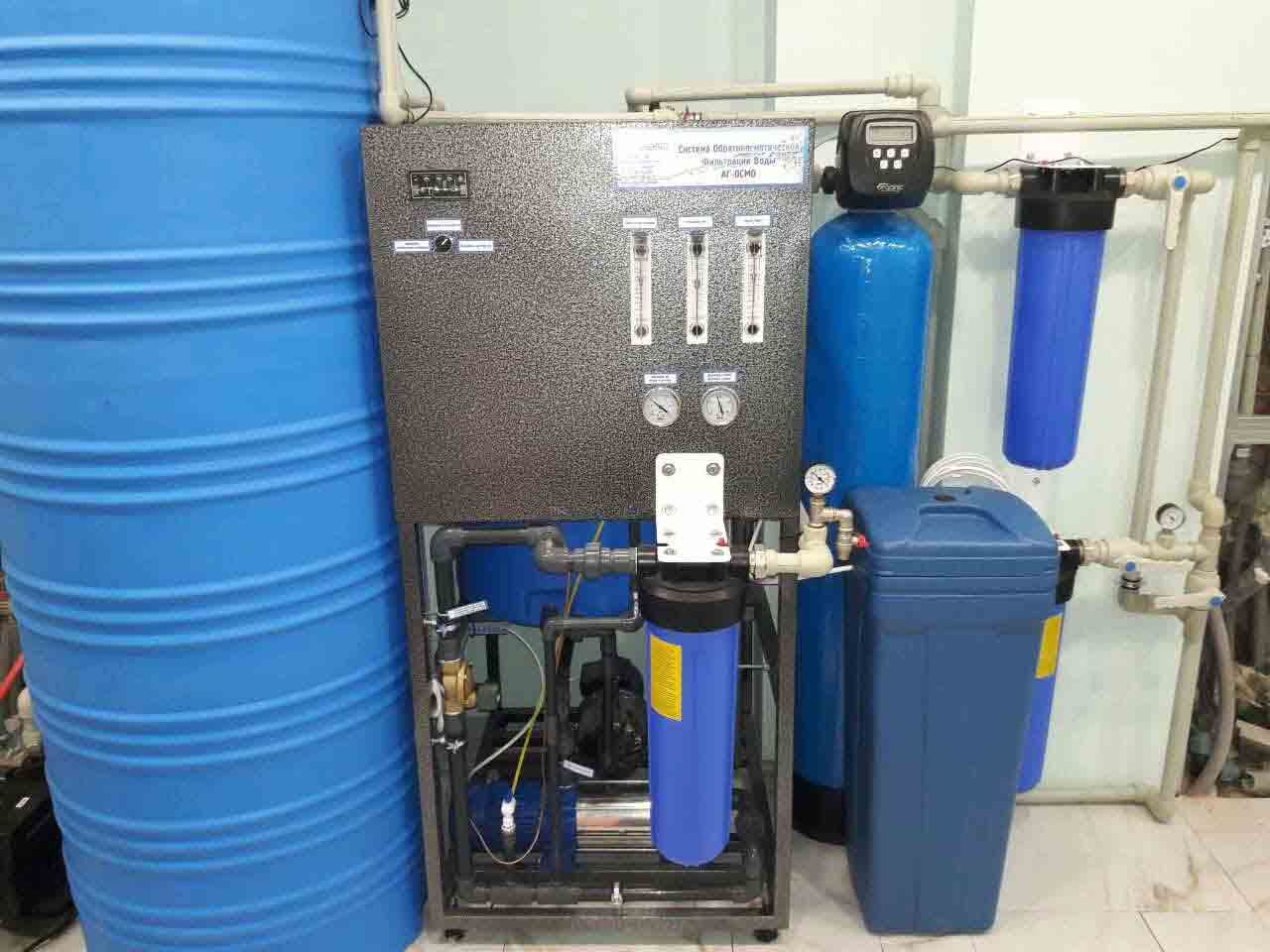 A complete whole-house reverse osmosis (RO) system installed in a utility room, showing the RO unit, large blue water storage tank, and pre-treatment filters