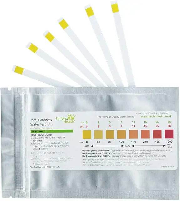 A close-up of a water hardness test strip being compared to a color chart.
